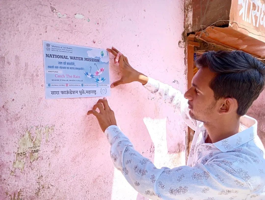 A volunteer putting up a National Water Mission poster, 2023