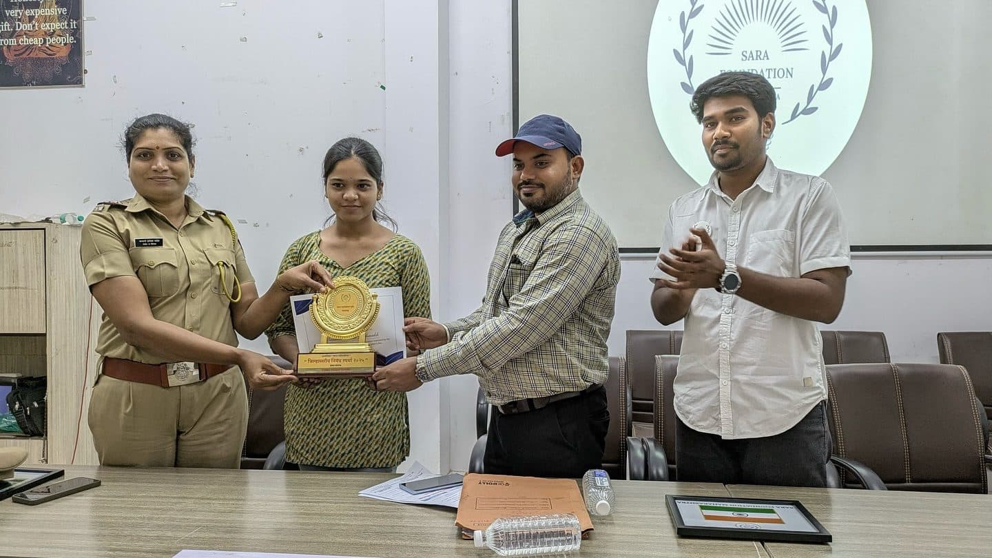 A woman police officer presents a trophy to an essay-competition winner, March 2025